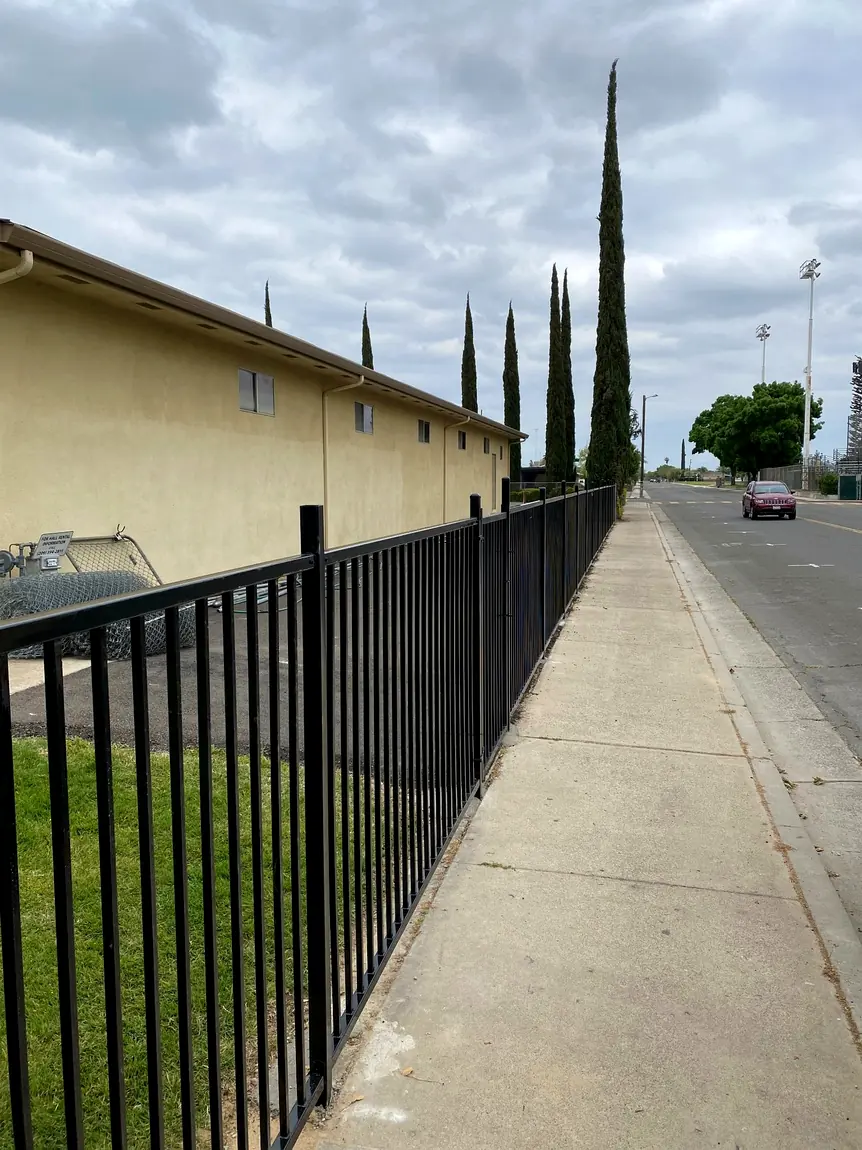 Black ornamental fence along a sidewalk